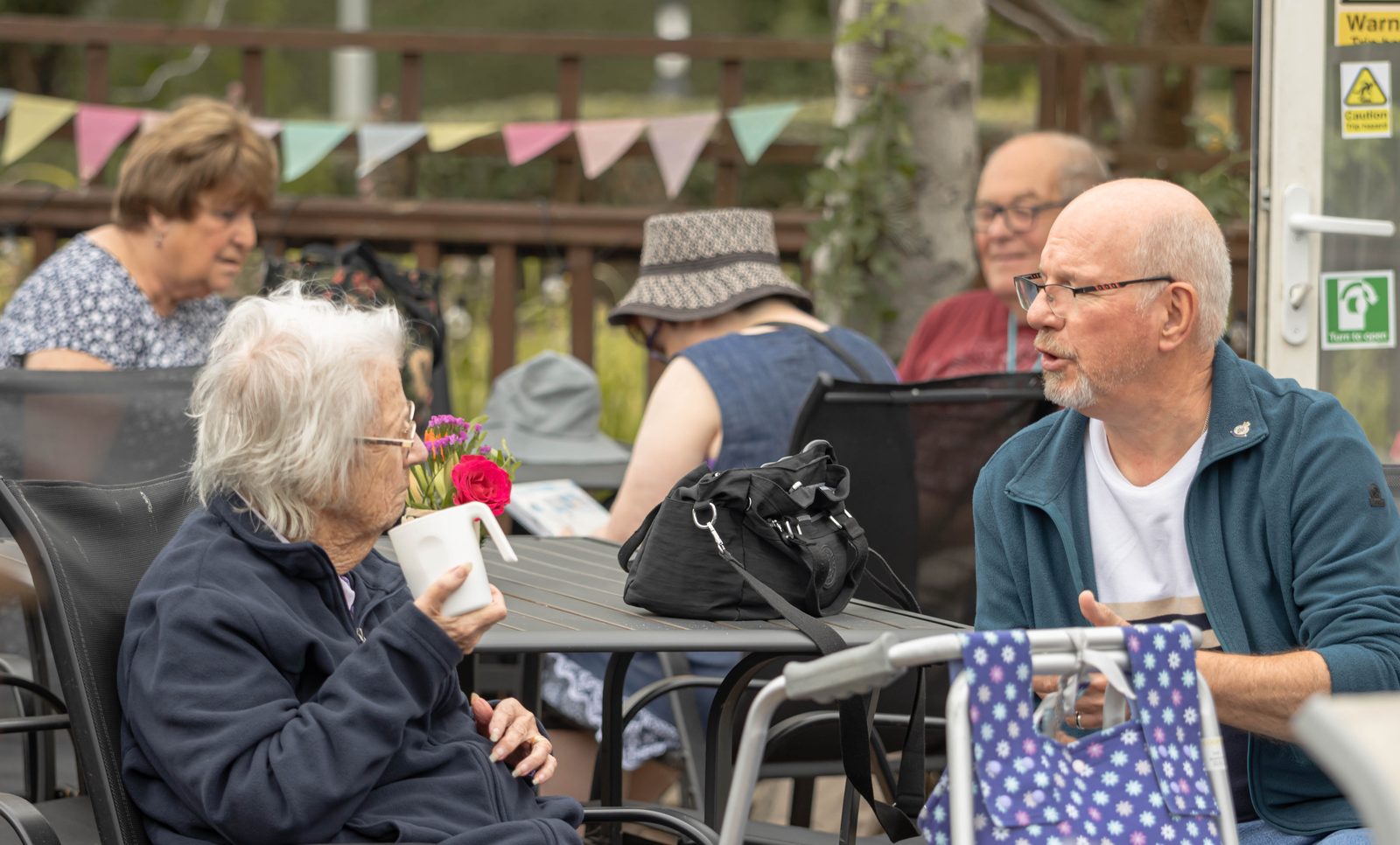 A resident in conversation with a visitor on the patio