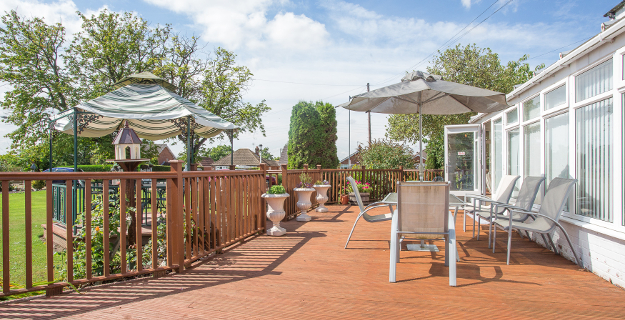 The decked patio with parasols looking out over the garden